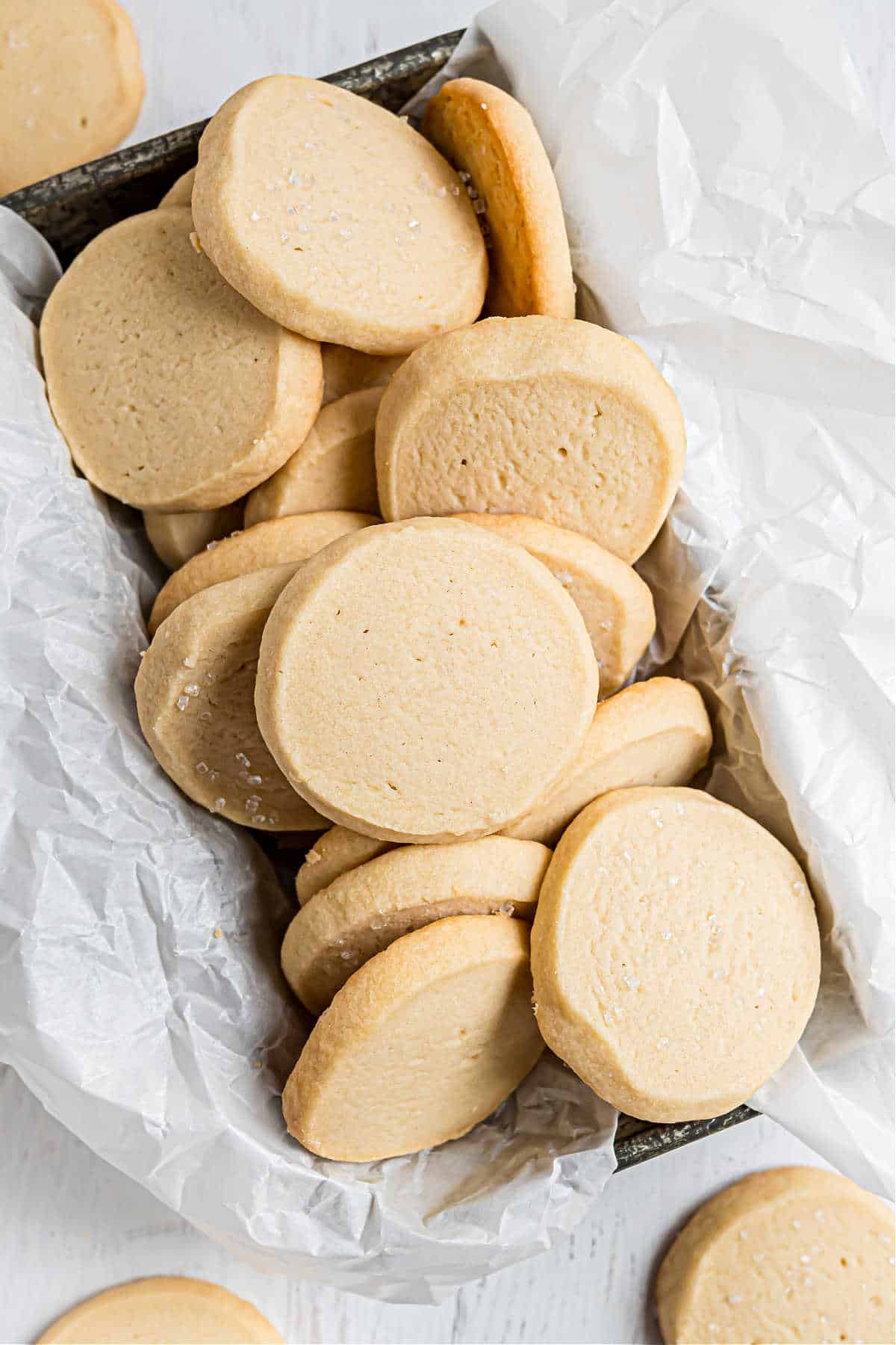 Shortbread cookies stacked in a bread loaf pan lined with parchment paper.