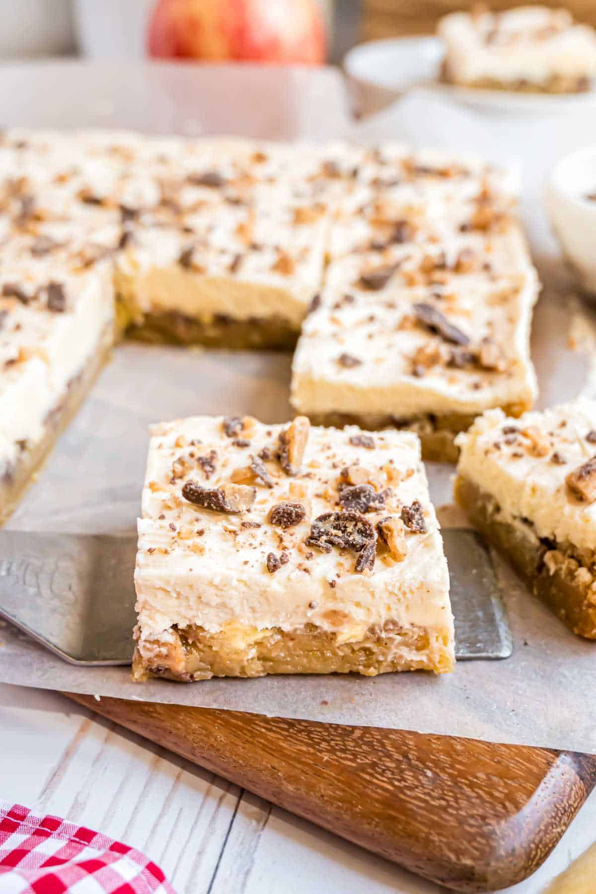 Blondies with frosting on a wooden cutting board.