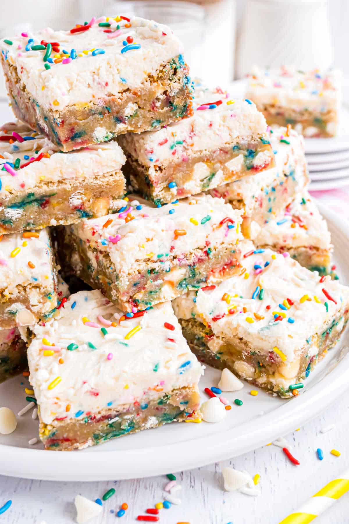 Frosted blondies stacked on a white plate.