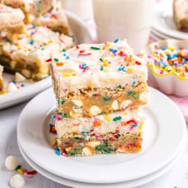 Two frosted funfetti blondies on a white plate.