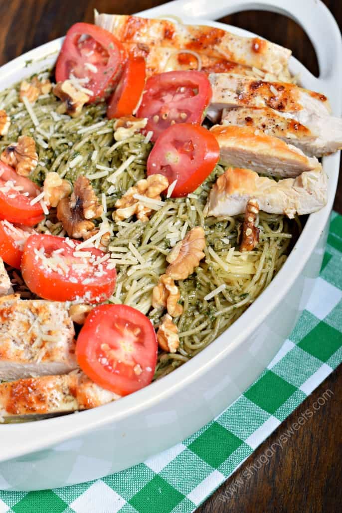 Pesto Pasta in a baking dish with chicken, tomatoes, and walnuts.