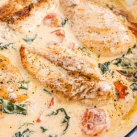 Tuscan garlic chicken features creamy chicken breasts with spinach and cherry tomatoes in a rich, flavorful sauce, delicately seasoned with black pepper.