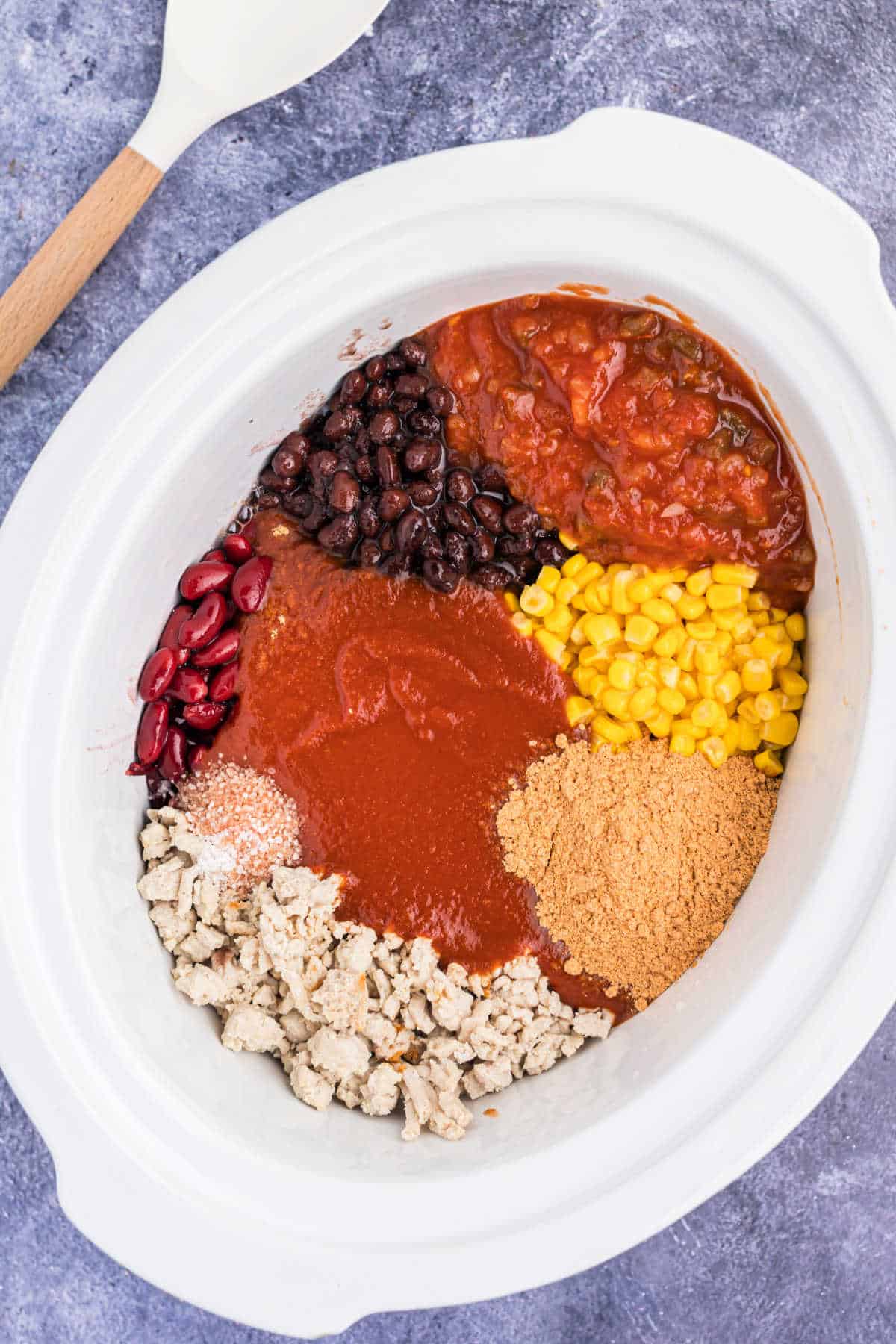 Ingredients for taco chili in a white crockpot.