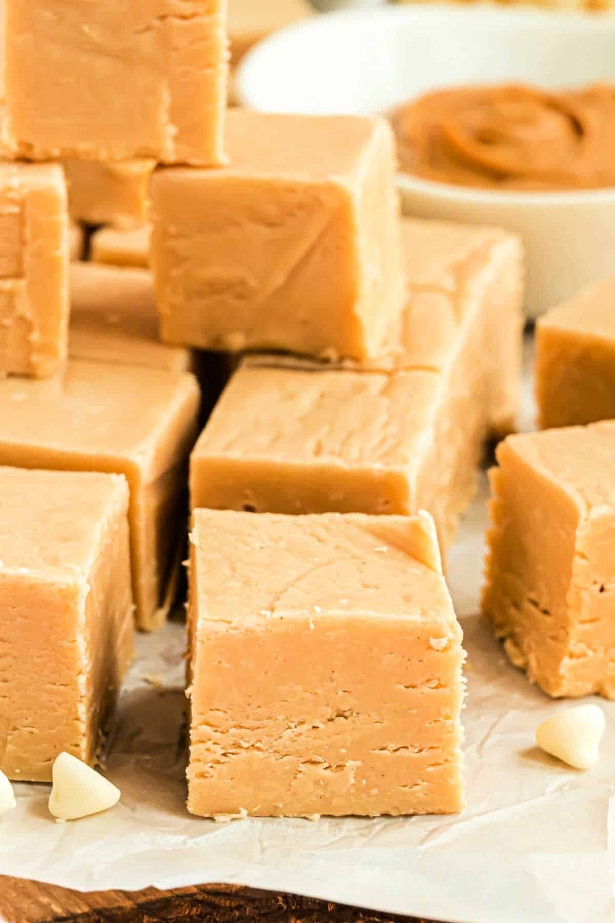 Bites of peanut butter fudge stacked on parchment paper.