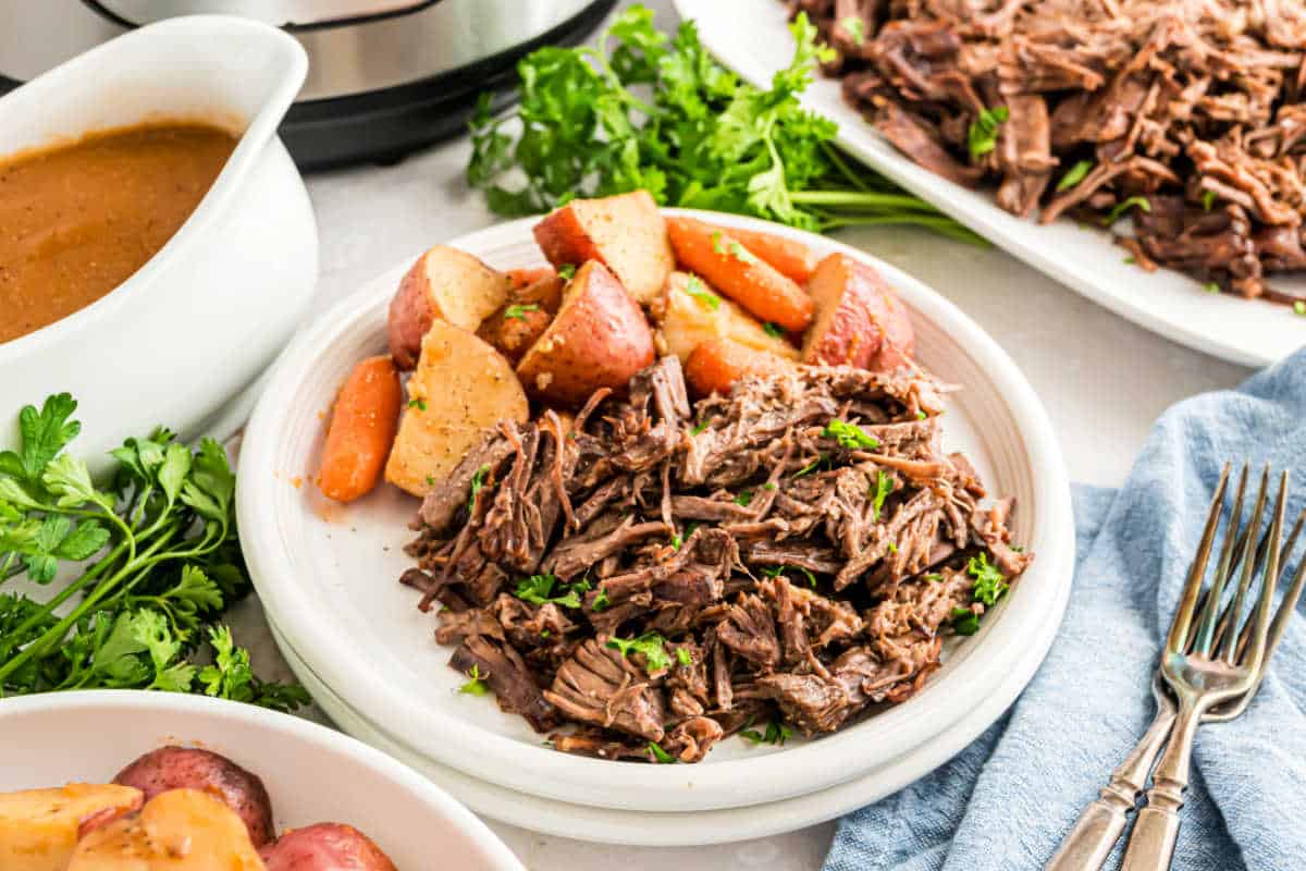 Pot roast served on a dinner plate with a side of gravy.