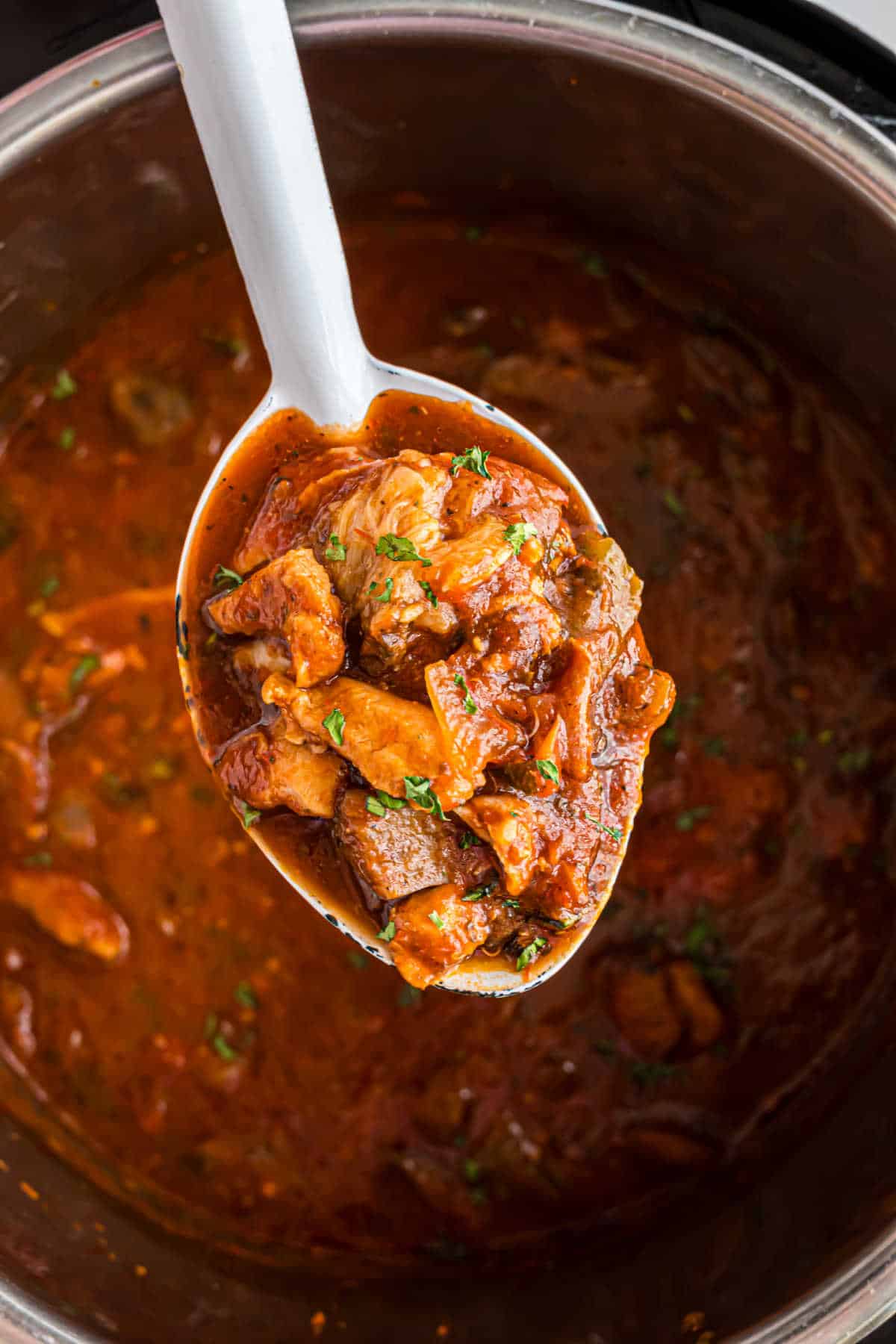 Chicken cacciatore in the pressure cooker with a spoon.