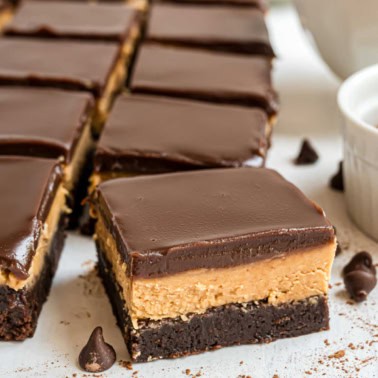 Layered chocolate and peanut butter brownies on parchment paper.