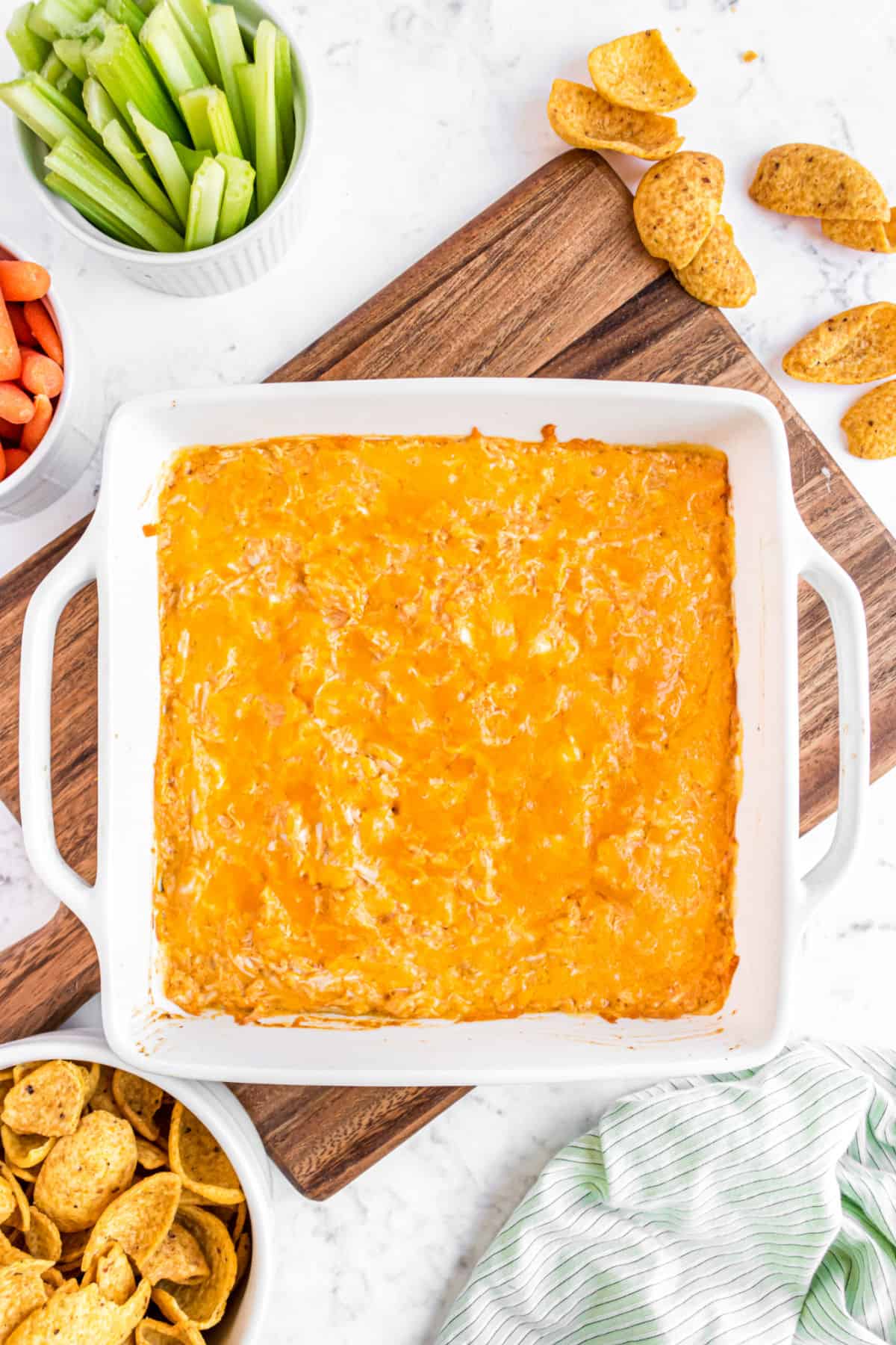 Baking dish with buffalo chicken dip and vegetables on the side.