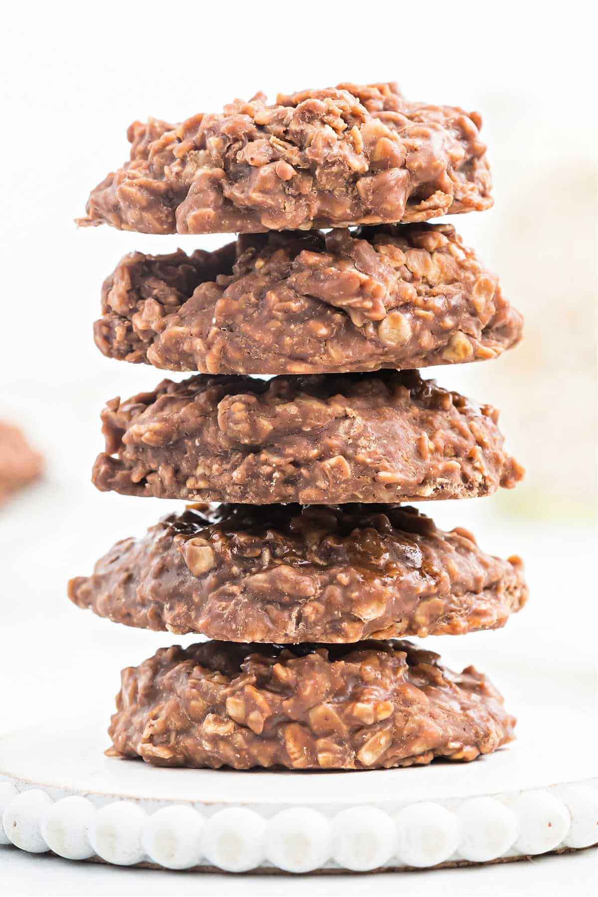 Stack of 5 chocolate no bake oatmeal cookies on a white platter.