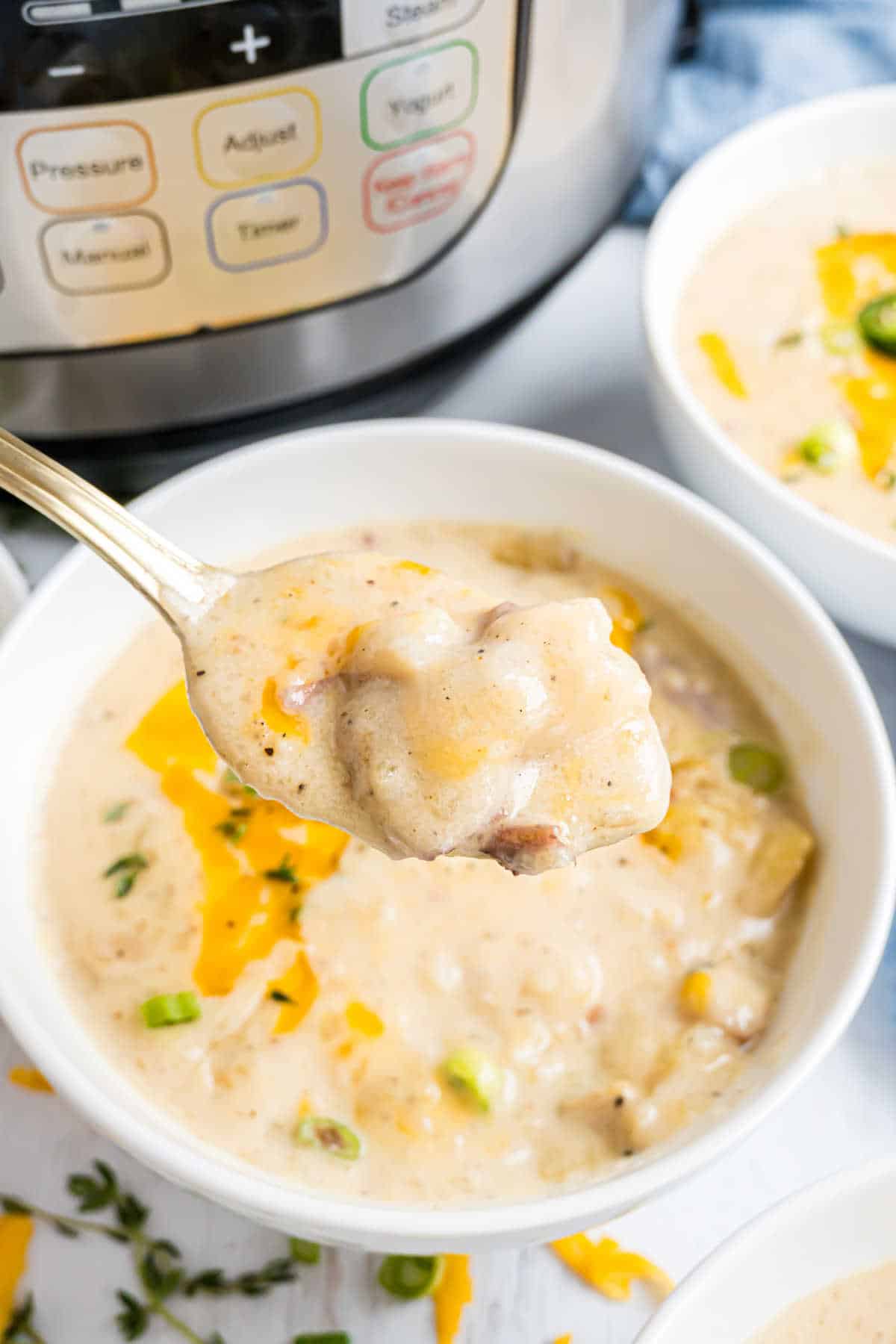 White bowl filled with creamy potato soup topped with cheese.