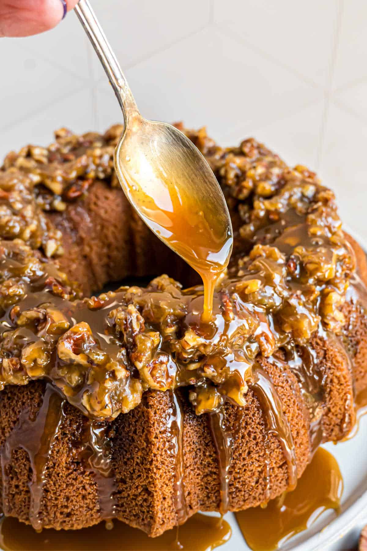 Caramel sauce being drizzled on pecan pie cake.