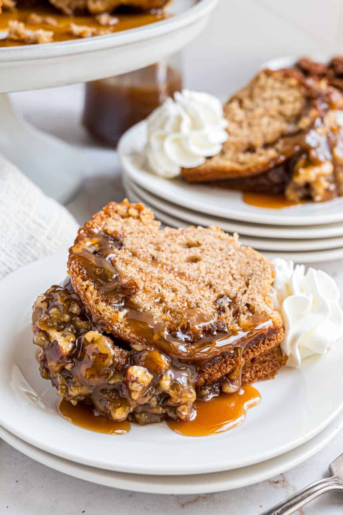 Slice of pecan pie bundt cake served on a plate with whipped cream.