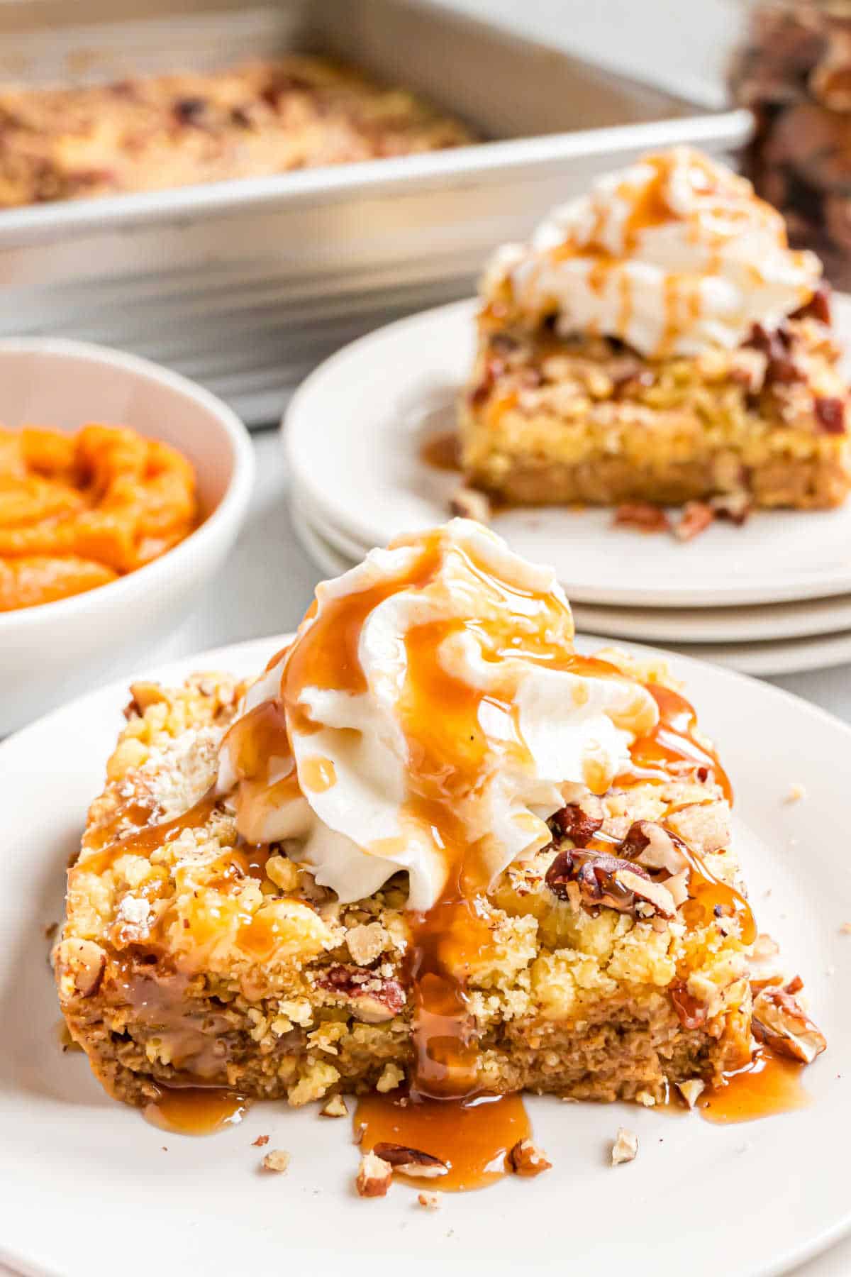 Slice of pumpkin dump cake on a plate with whipped cream and caramel sauce.