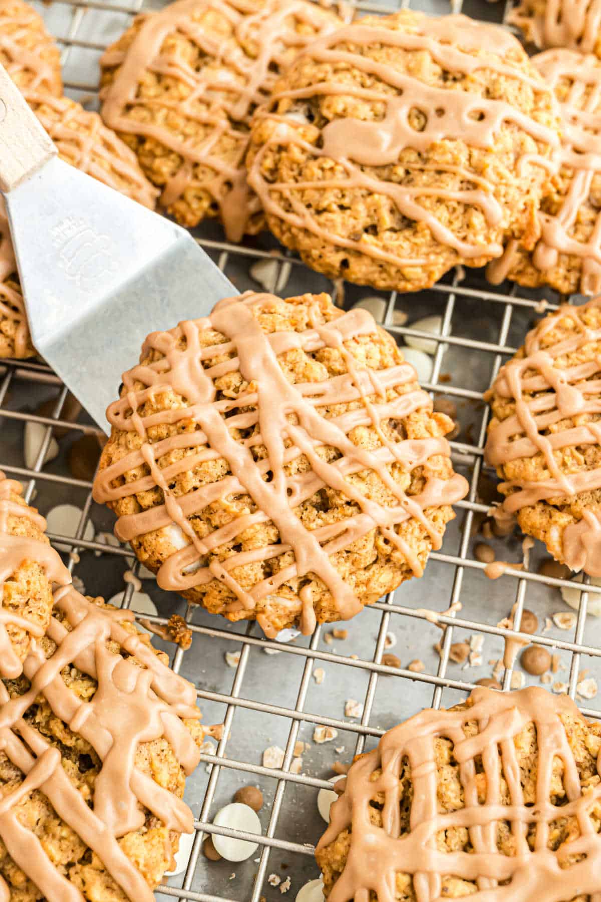 Pumpkin cookies on a wire rack and drizzled with icing.