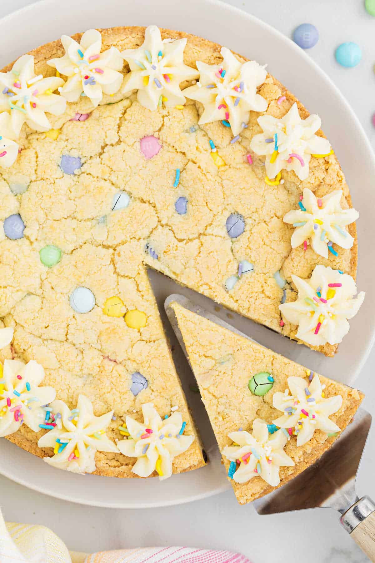 Slice of sugar cookie cake being removed from plate.