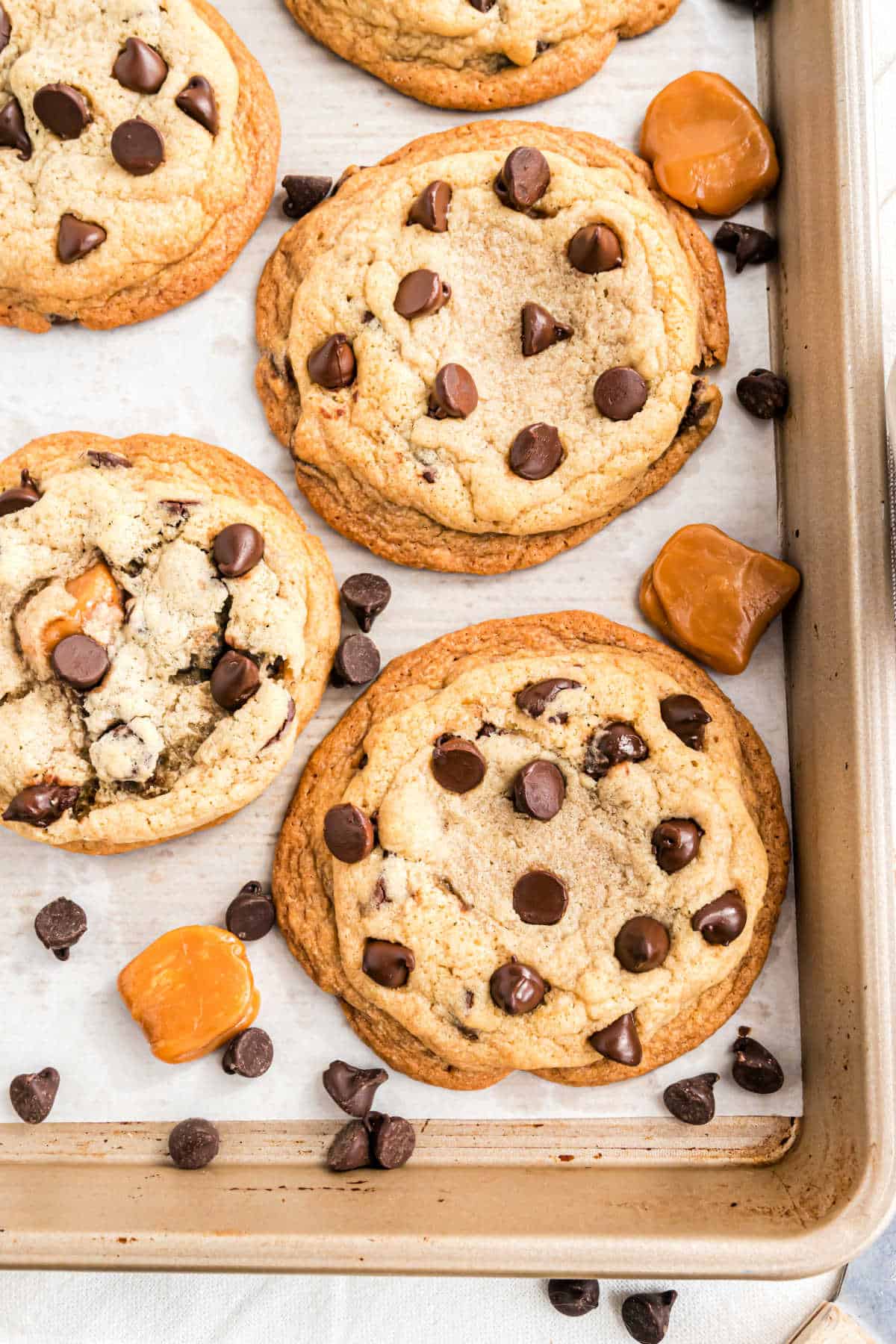 Caramel stuffed chocolate chip cookies on a cookie sheet.