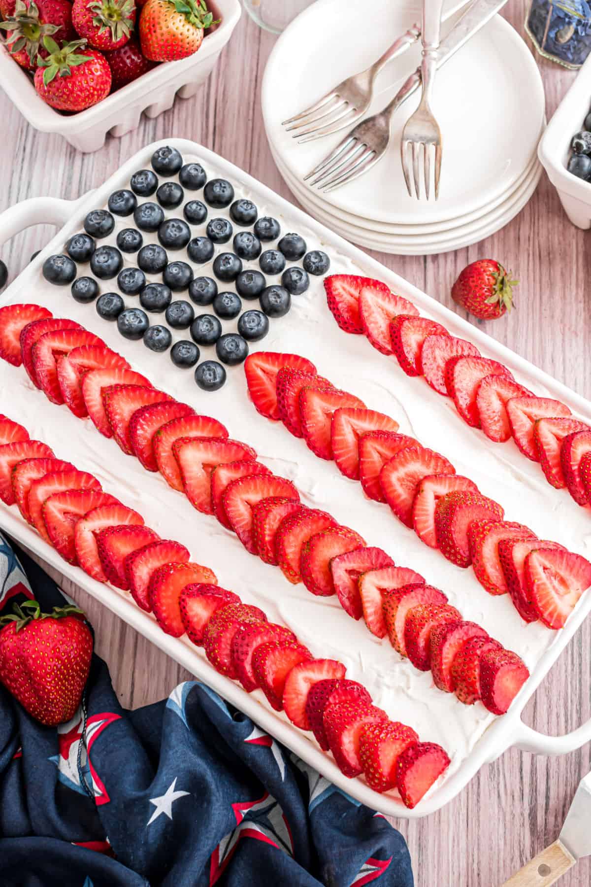 Red white and blue flag cake using whipped cream, blueberries, and strawberry slices.
