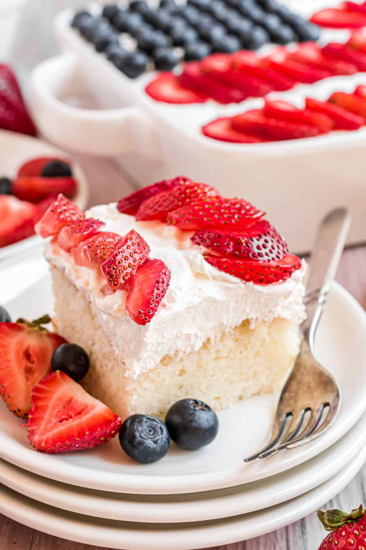 Slice of white cake with whipped cream and berries to resemble a flag.