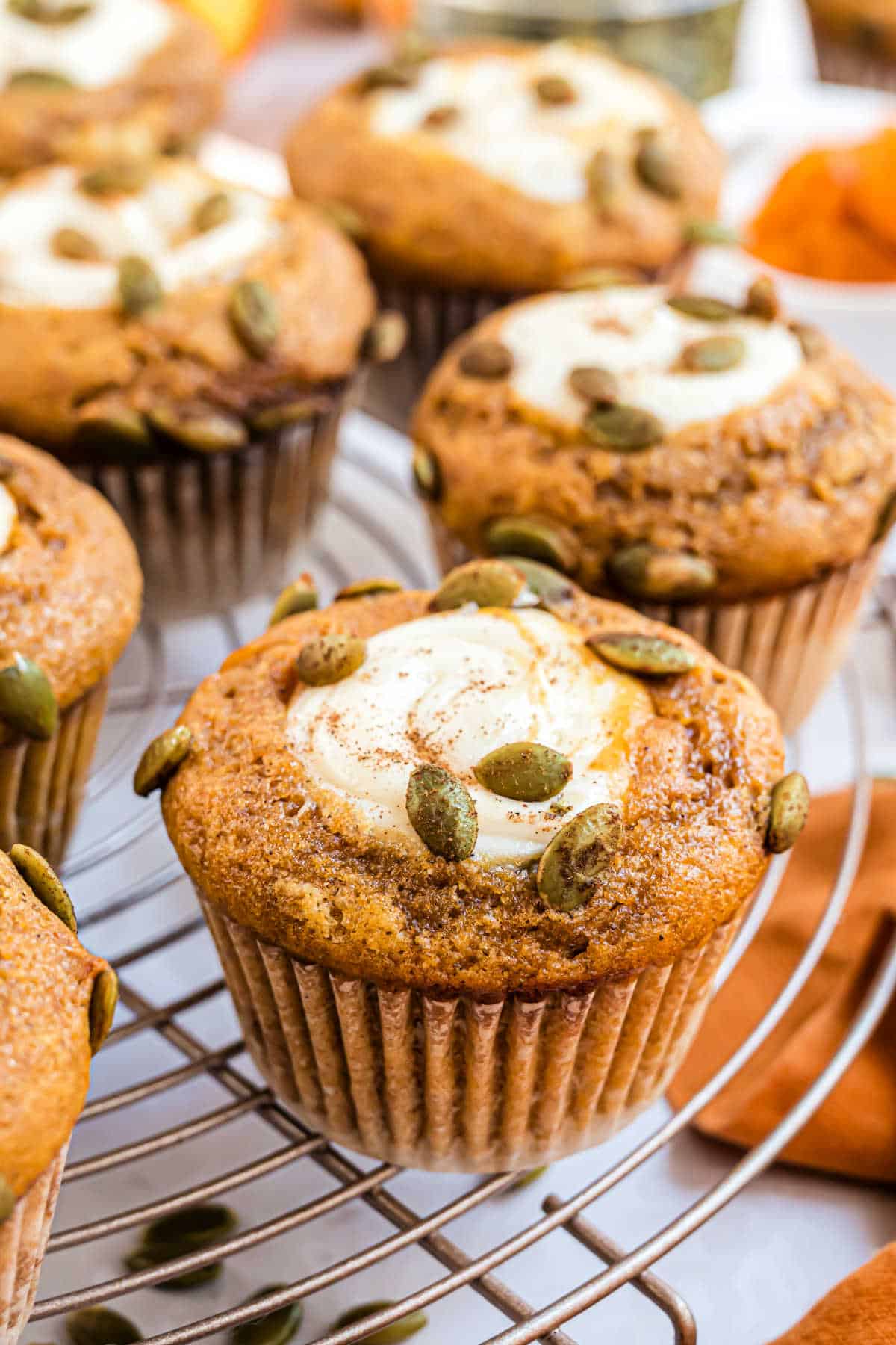 Pumpkin muffins filled with cream cheese filling on a wire cooling rack.