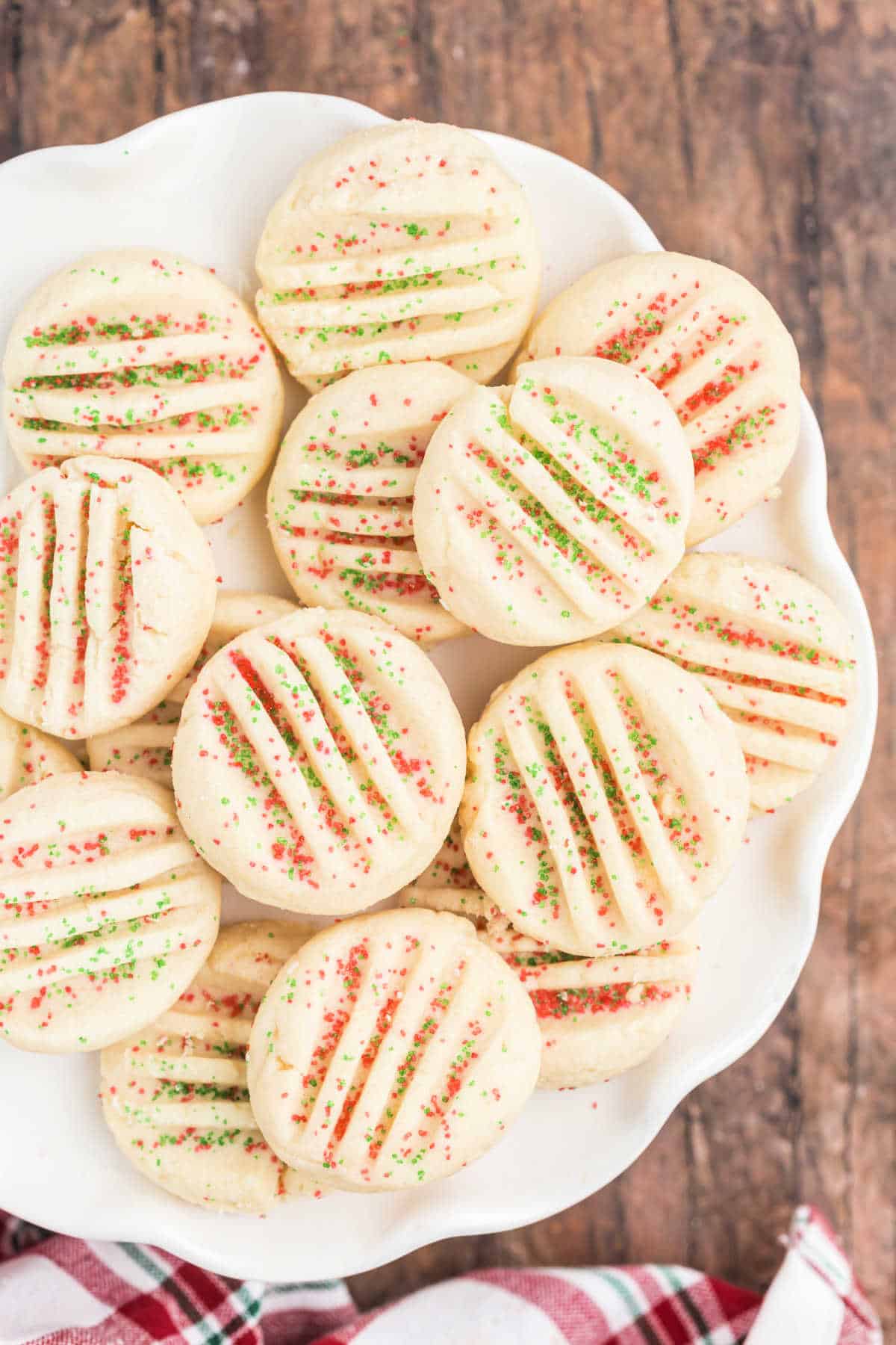 Whipped shortbread cookies on a white plate with holiday sanding sugar.