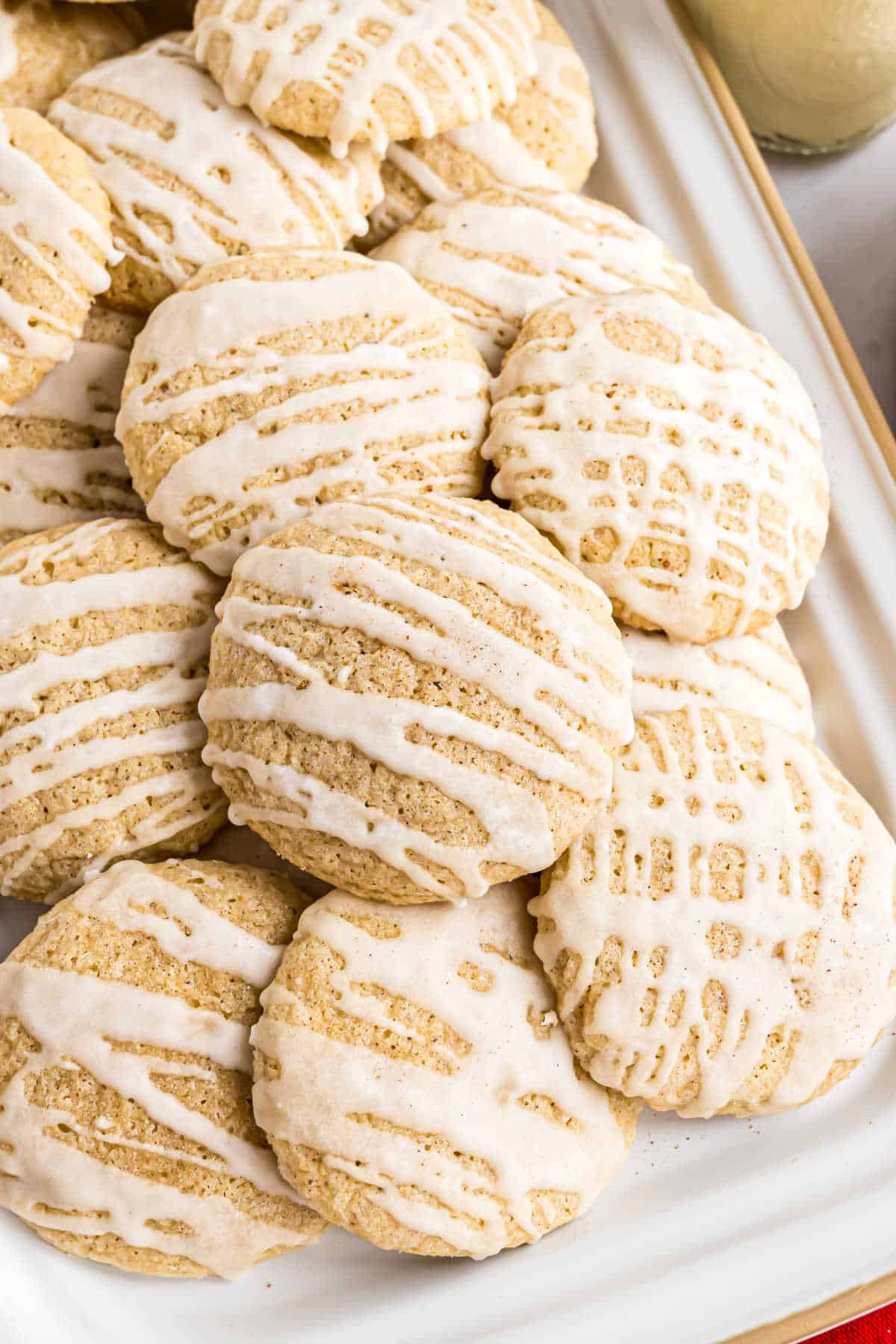 Iced eggnog cookies stacked on a white plate.