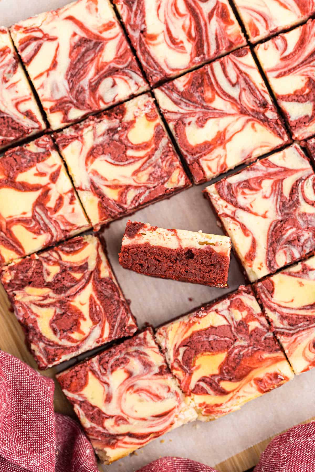 Red velvet cheesecake brownies cut on parchment paper.