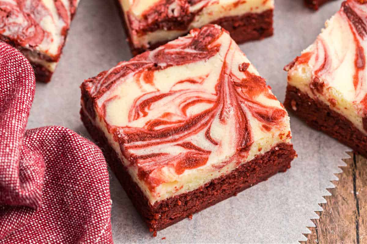 Cheesecake swirled red velvet brownies on parchment paper.