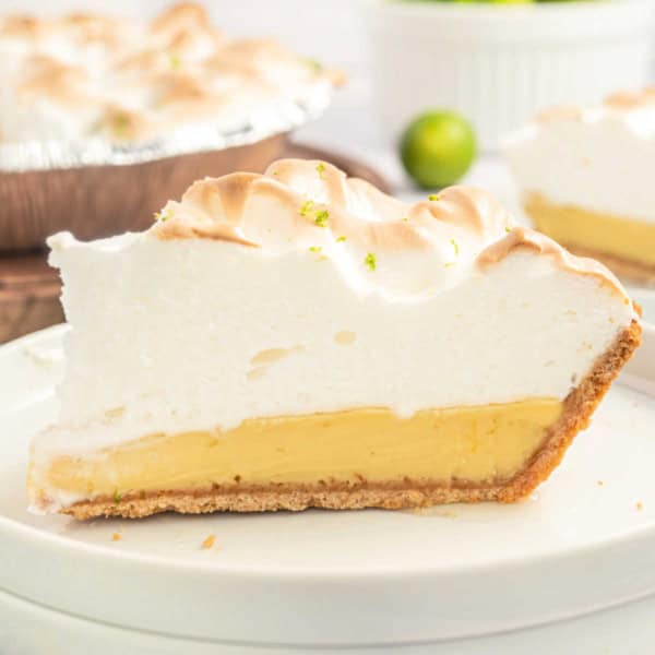 Slice of key lime pie with meringue on a white plate.