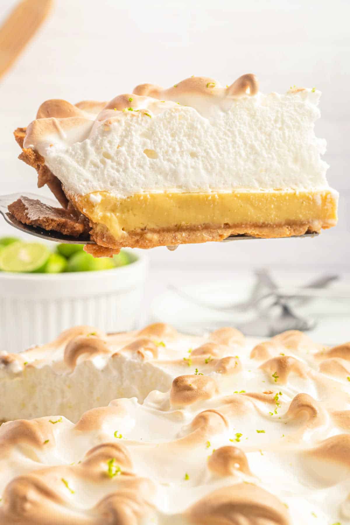 Slice of key lime meringue pie being lifted out of pie plate.