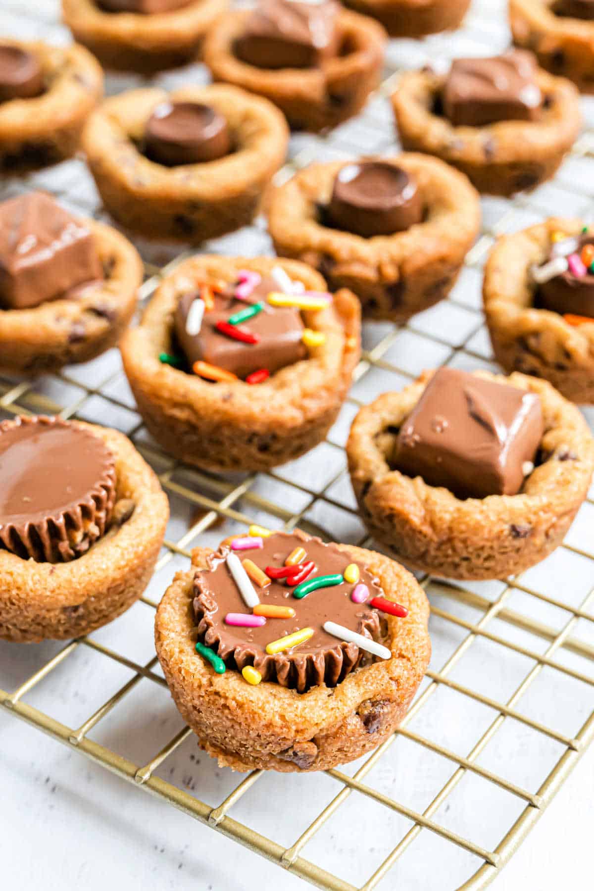 Chocolate chip cookie cups with candy pressed in the center and topped with sprinkles.