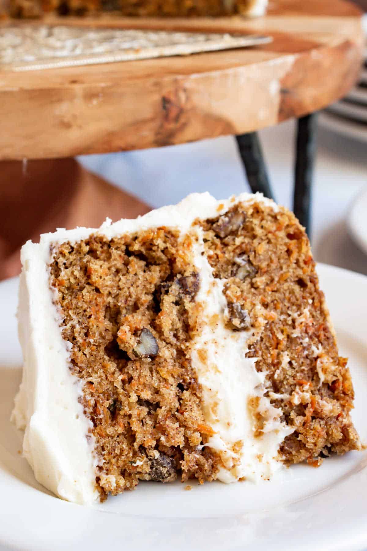 Slice of frosted carrot cake on a white plate.