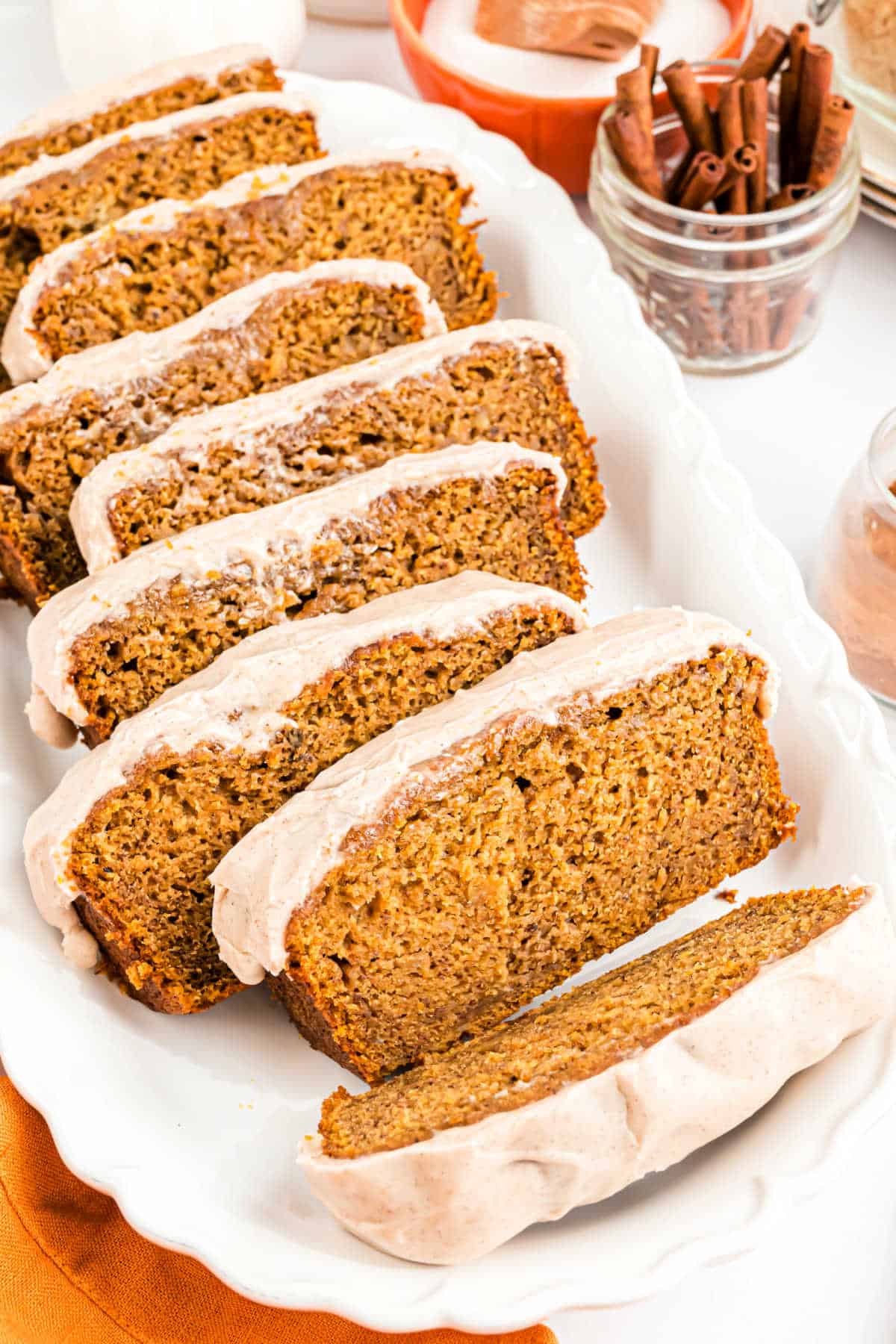 Pumpkin iced banana bread on a white serving plate.