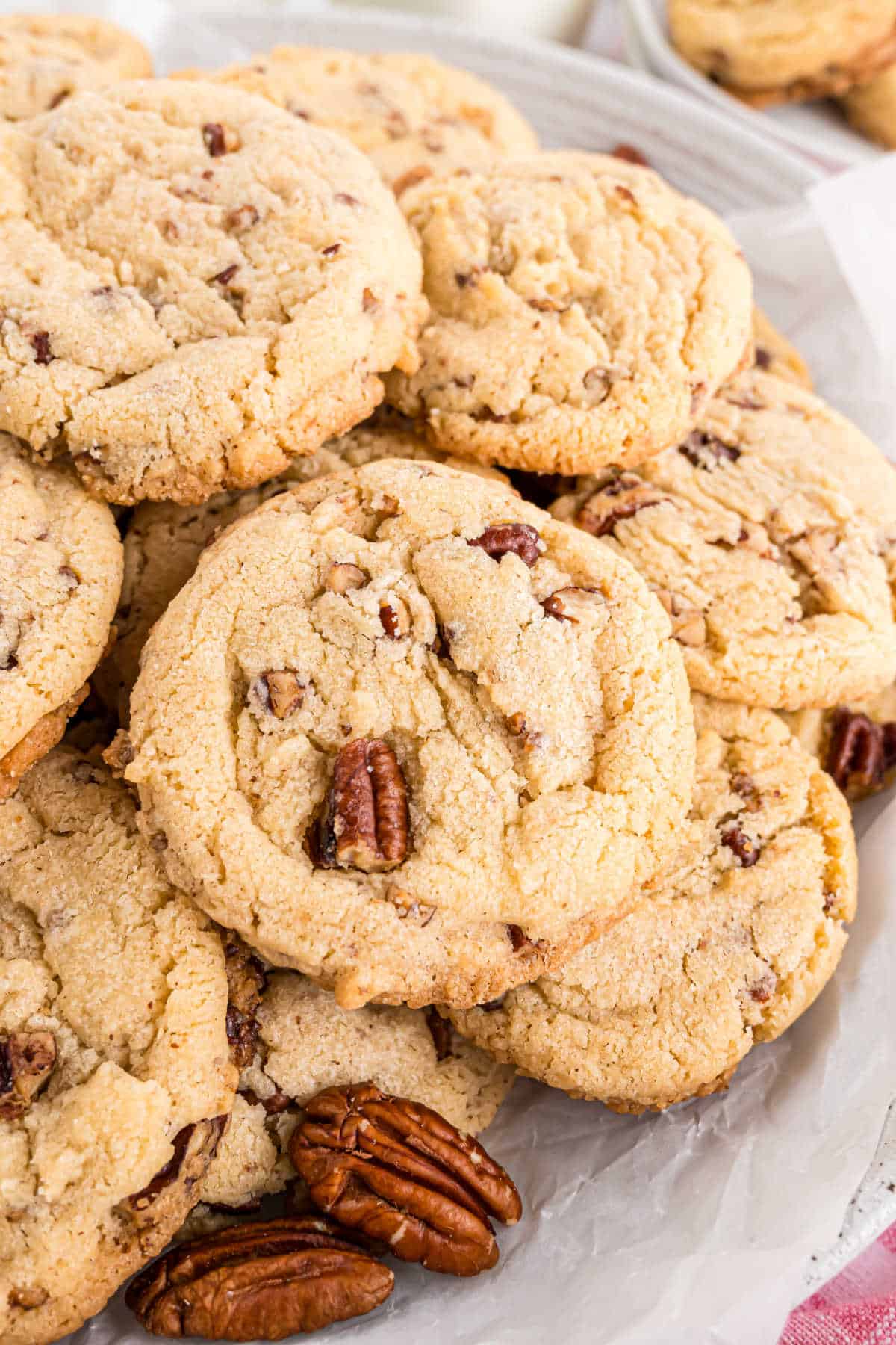 Buttery pecan cookies stacked on a white plate.