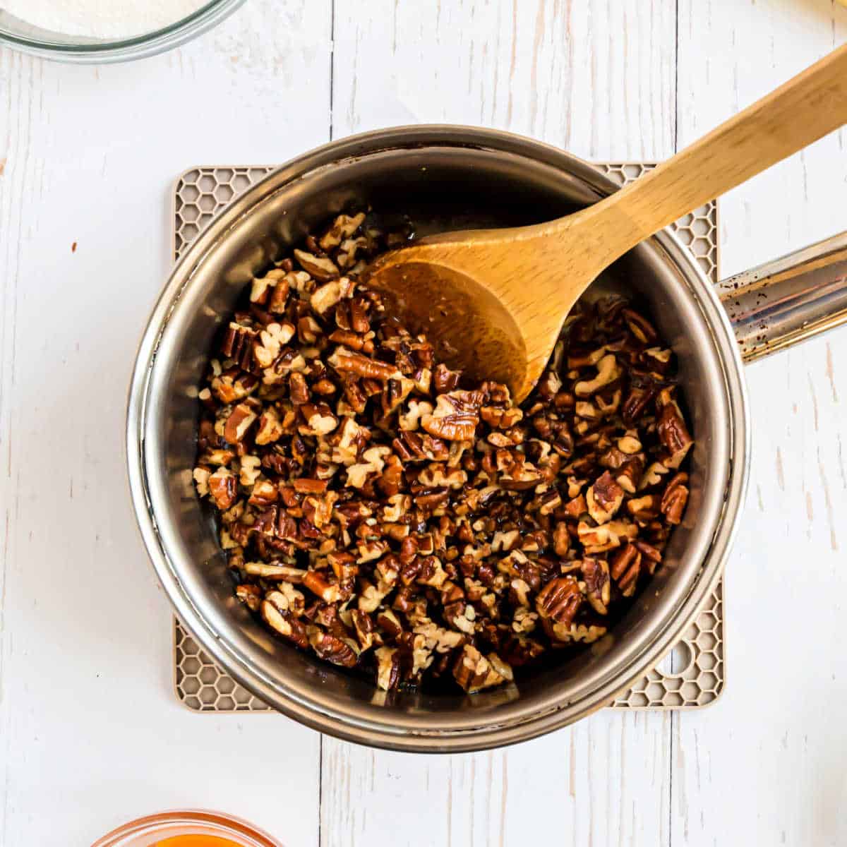 Pecans in a saucepan with melted butter.