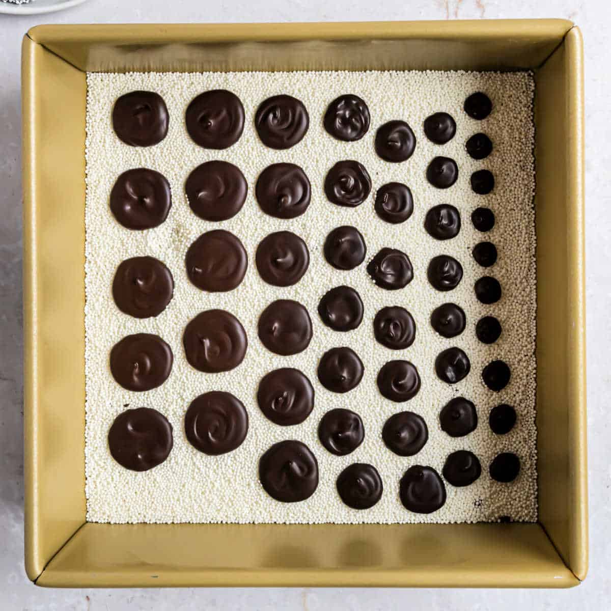 Various sizes of chocolate nonpareils in a baking dish.