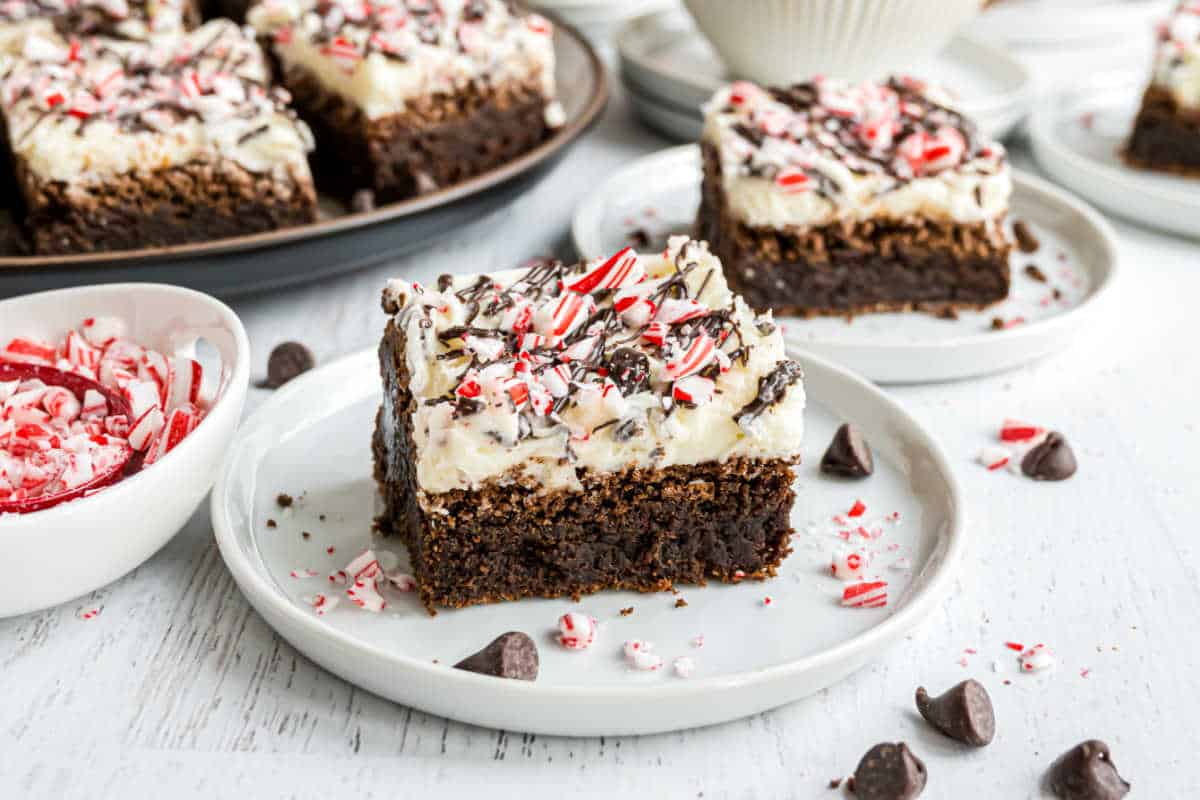 Two brownies with peppermint frosting on a white dessert plates.