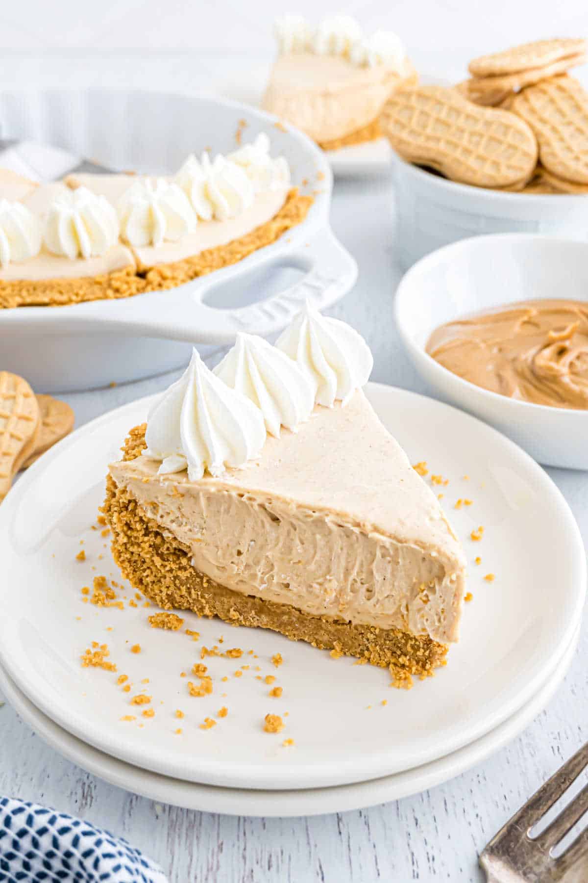 Slice of no bake peanut butter pie on a stack of white plates.