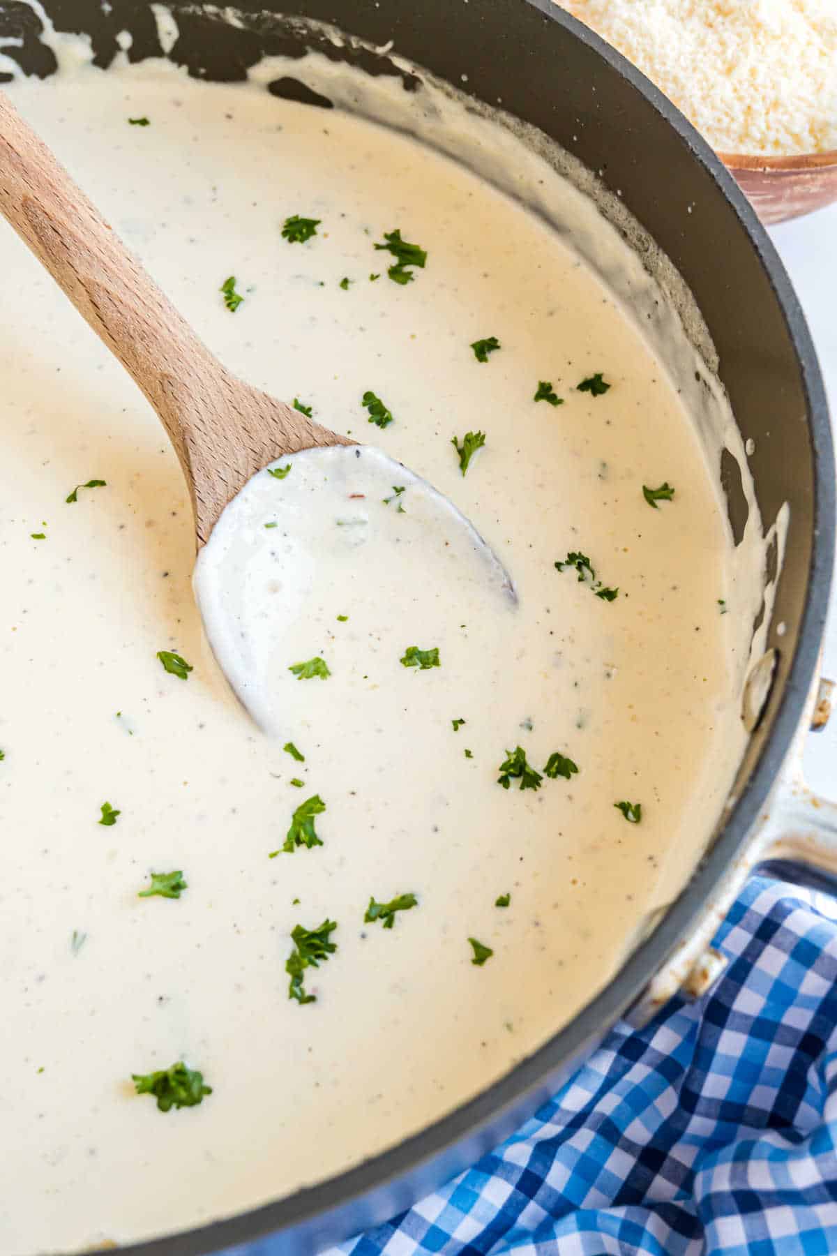 Alfredo sauce thickened in a skillet and sprinkled with parsley.