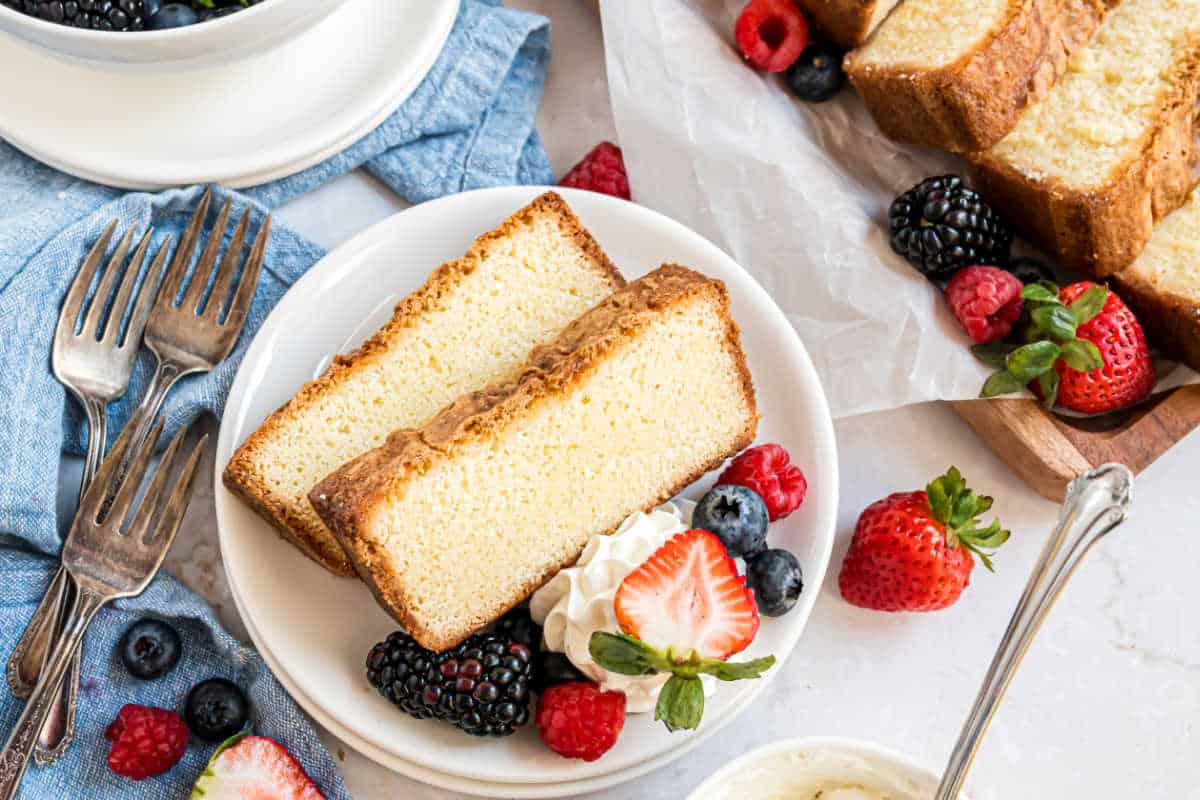 Two slices of pound cake on a plate with berries.