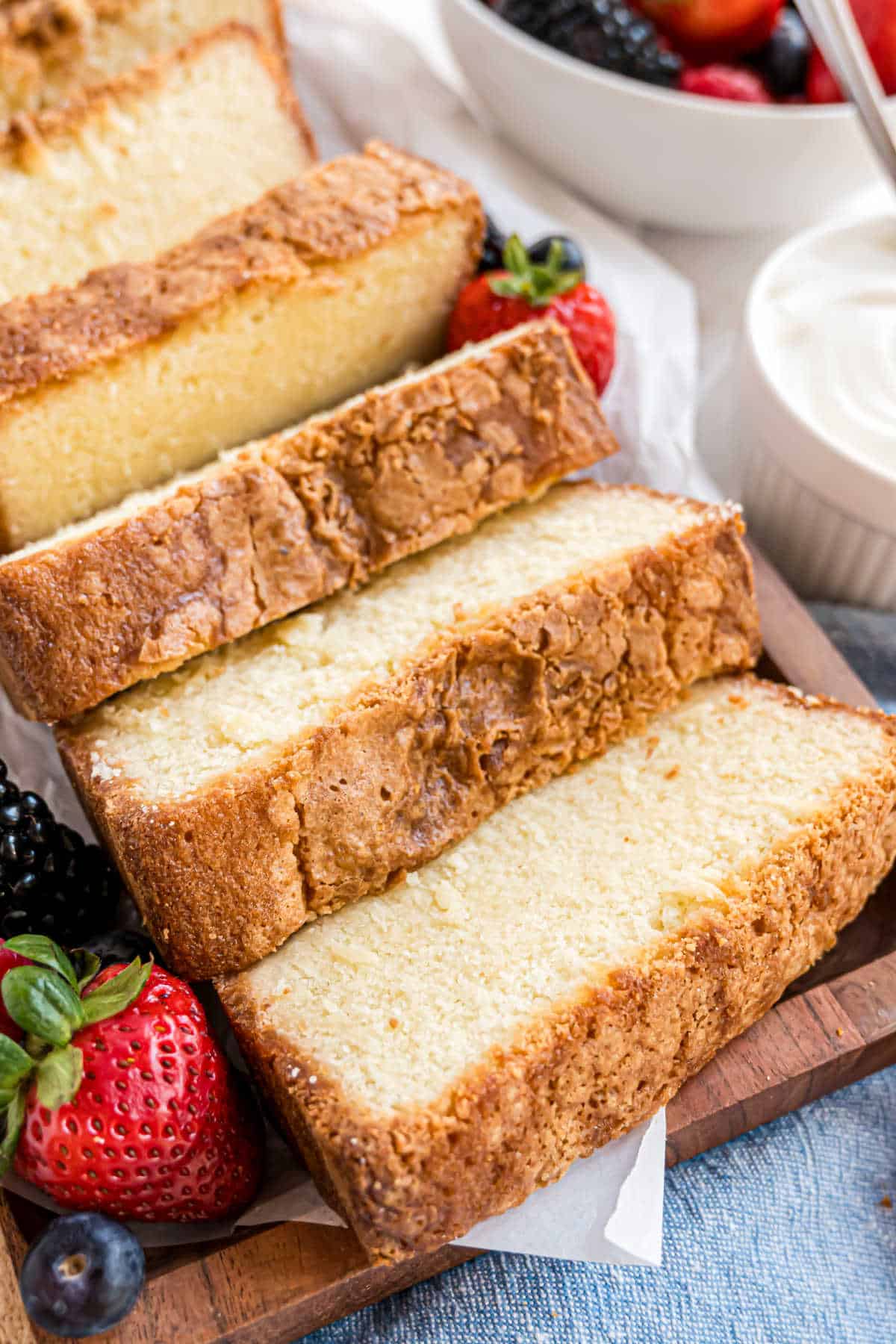 Slices of pound cake on a cutting board with berries.