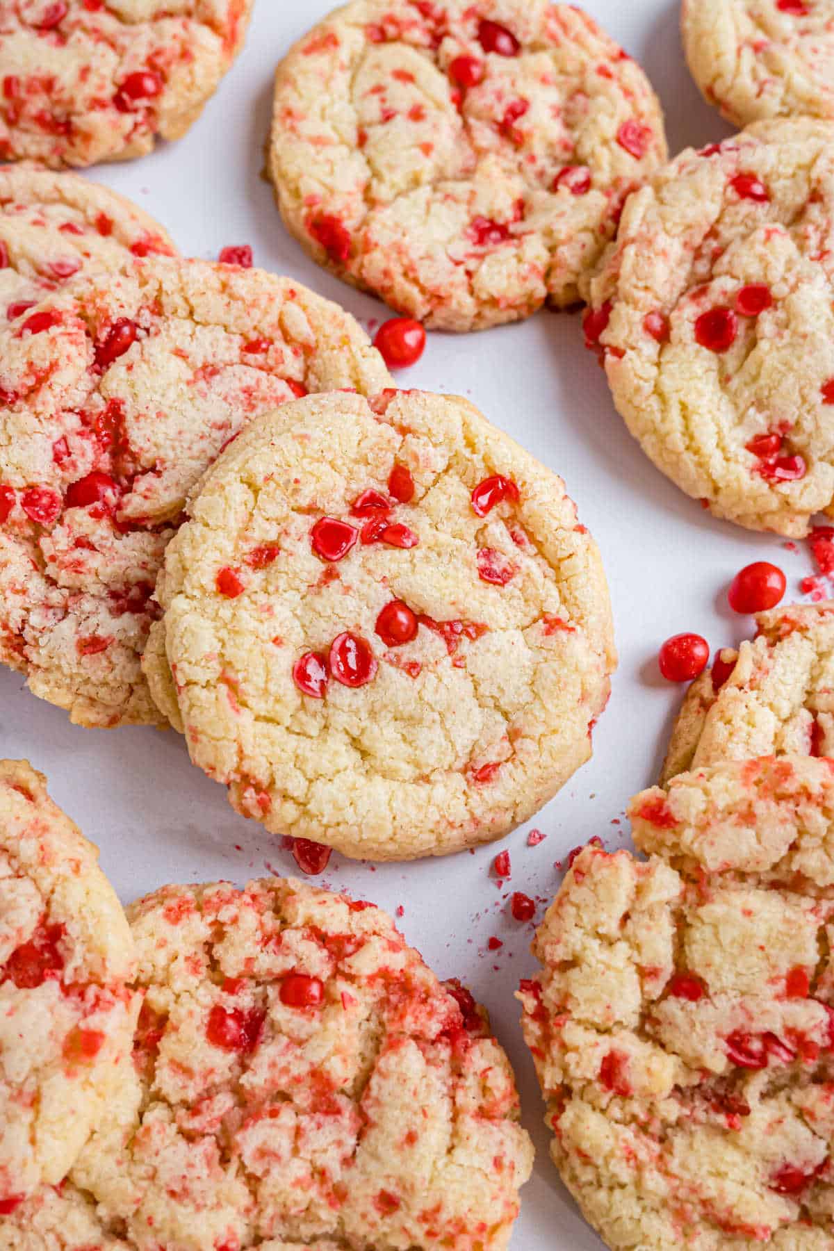 Stacks of sugar cookies with red hot candy on parchment paper.