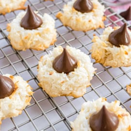 Coconut blossom cookies topped with chocolate kisses are cooling on a wire rack.