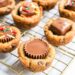 Cookies pressed with reeses cups and sprinkles on a wire rack.