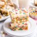 Two frosted funfetti blondies on a white plate.