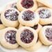 Stacks of jam thumbprint cookies on a white plate.