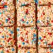 Rice krispy treats cut into squares and decored with red white and blue sprinkles.
